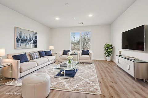 A modern living room with a glass coffee table and a large painting on the wall.