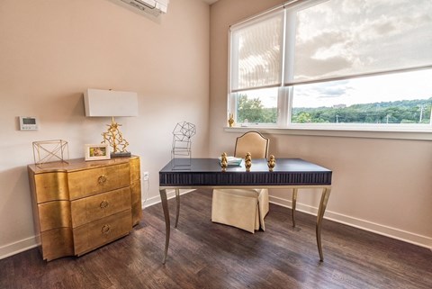 A gold dresser sits next to a black and white chair in a room with a window.