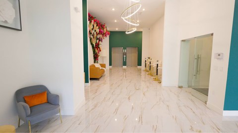 A hallway with a grey armchair and a white wall.