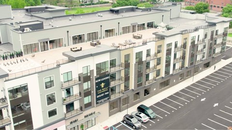 A street view of a multi-story building with cars parked in front.