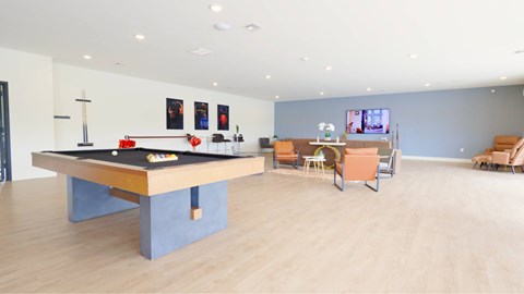 A room with a pool table and chairs.