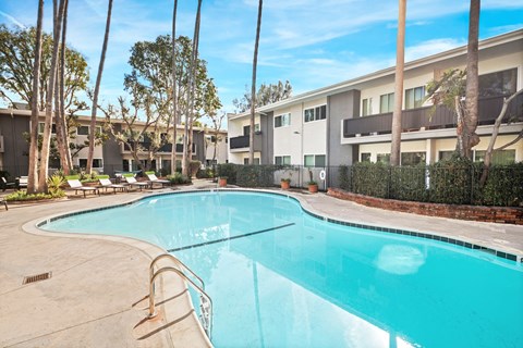 A swimming pool in front of a building with trees around it.