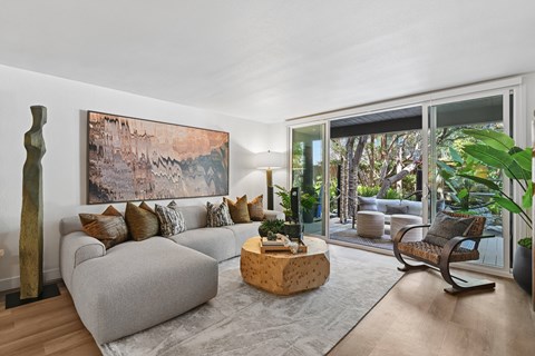 A living room with a grey couch and a large painting on the wall.