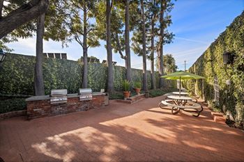A patio with a table and chairs surrounded by a wall of green plants at Villa Vicente, Los Angeles, CA, 90019