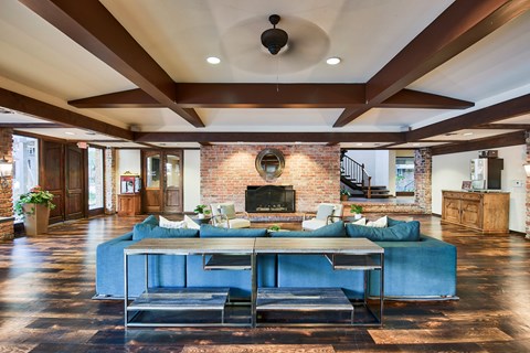 A large blue couch sits in the middle of a spacious room with a brick fireplace.