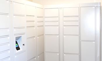 A row of white mailboxes are lined up on a wall.