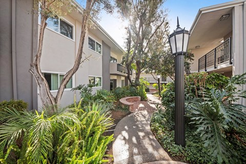 A black lamp post stands in front of a building with a small garden.