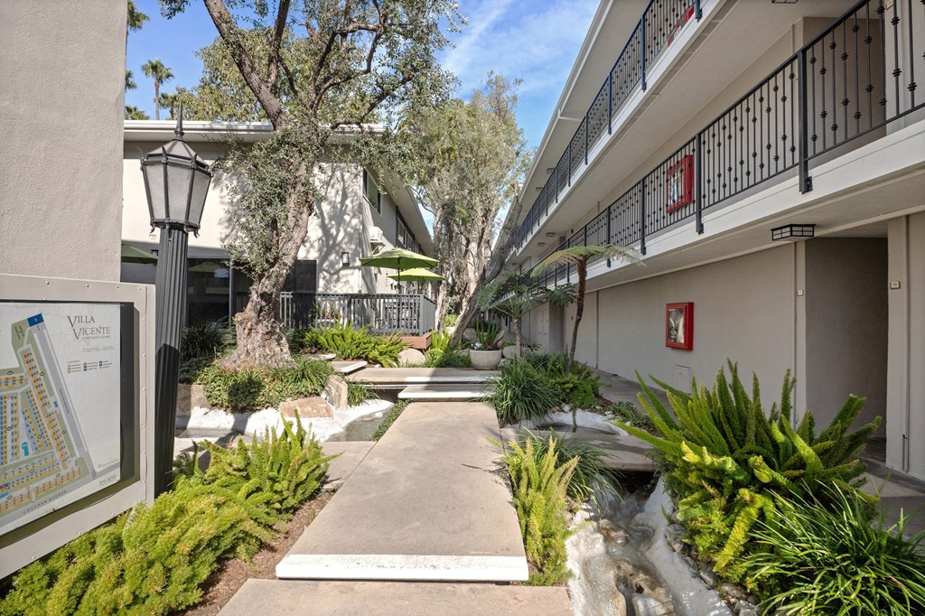 A pathway leads through a landscaped courtyard with a map of the area on the left at Villa Vicente, Los Angeles, CA