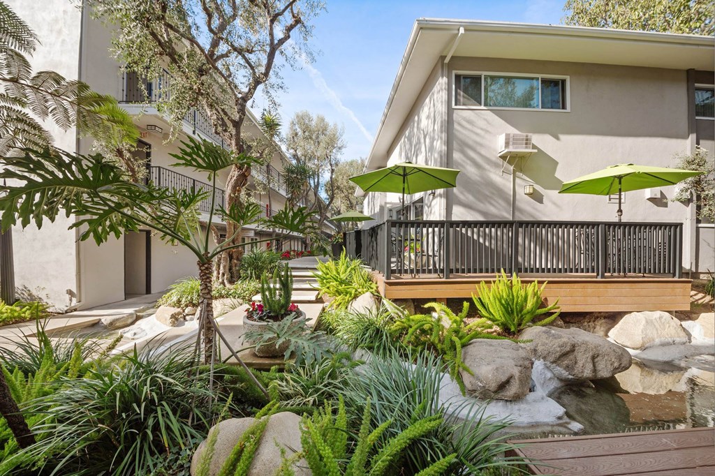 A patio with a table and chairs is surrounded by green plants at Villa Vicente, Los Angeles, CA