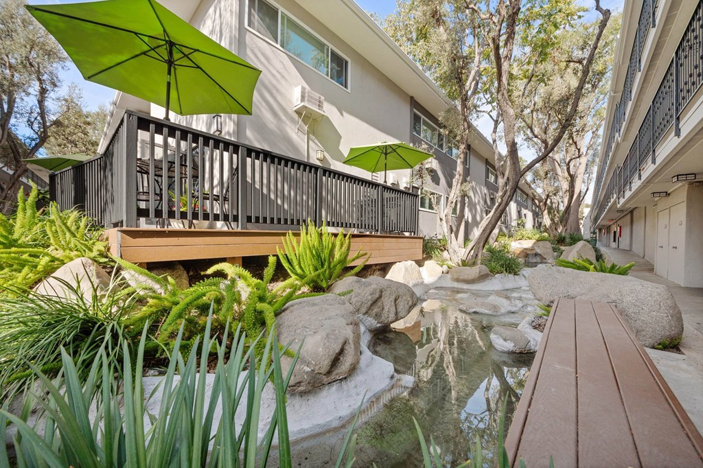 A green umbrella is on a balcony overlooking a water feature at Villa Vicente, Los Angeles, CA