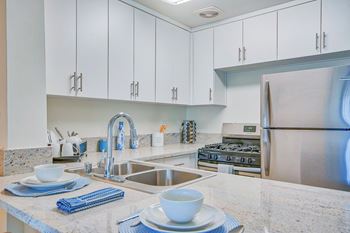 a white kitchen with stainless steel appliances and white cabinets at Villa Vicente, Los Angeles, CA