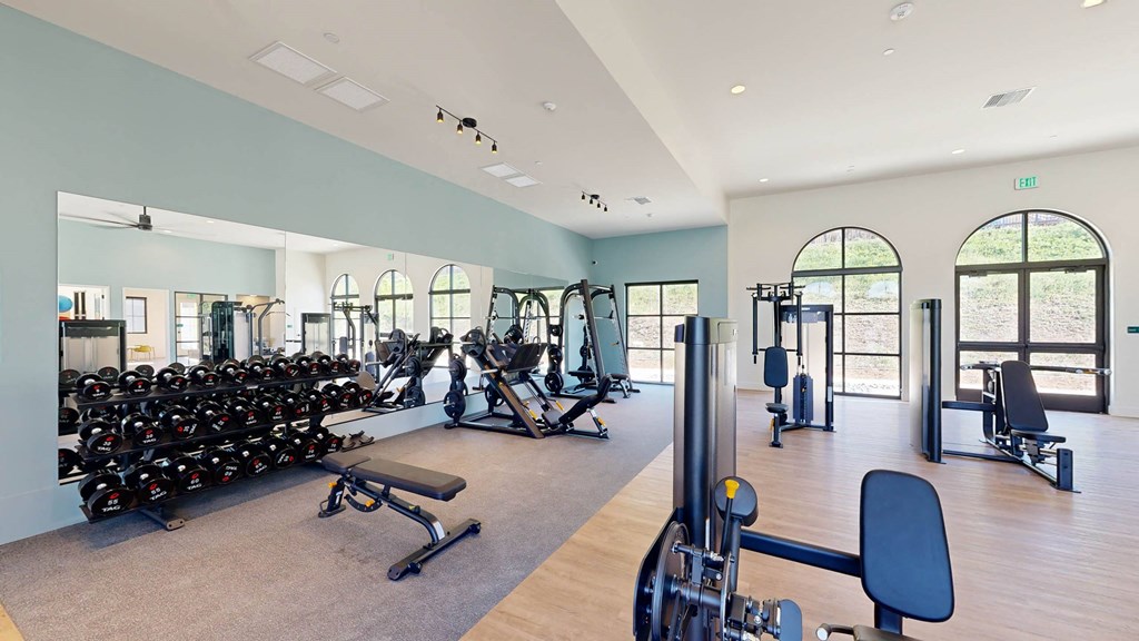 a gym with cardio equipment and weights in a building with windows at The Villas at Anacapa Canyon, Camarillo, California