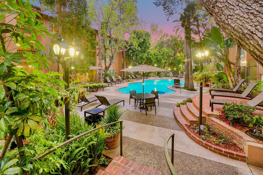 a backyard with a swimming pool and a patio with tables and chairs at Casa Granada, Los Angeles, CA, 90049