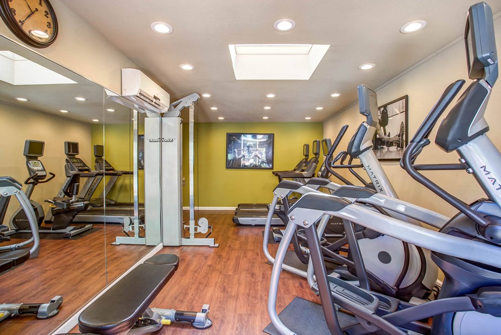 a gym with cardio equipment and a tv on the wall at Valley Plaza Villages, Pleasanton, CA