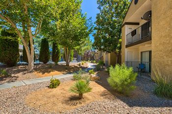 a courtyard with trees and plants in front of an apartment building