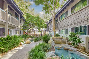 a courtyard with a waterfall and buildings with trees  at Rancho Los Feliz, California