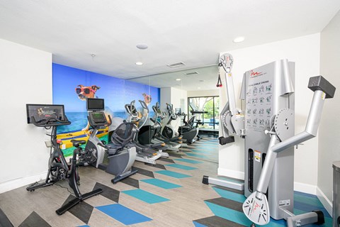 a gym with various cardio machines and a water fountain