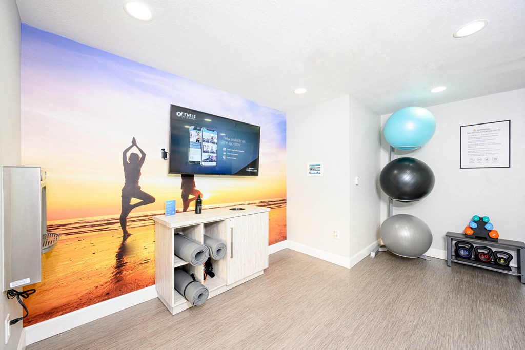 a yoga room with a large screen tv and a yoga ball