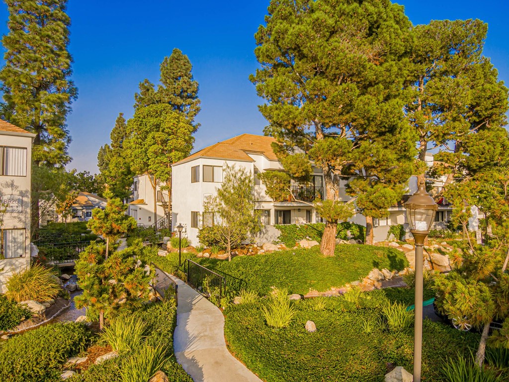 a garden with trees and a house in the background