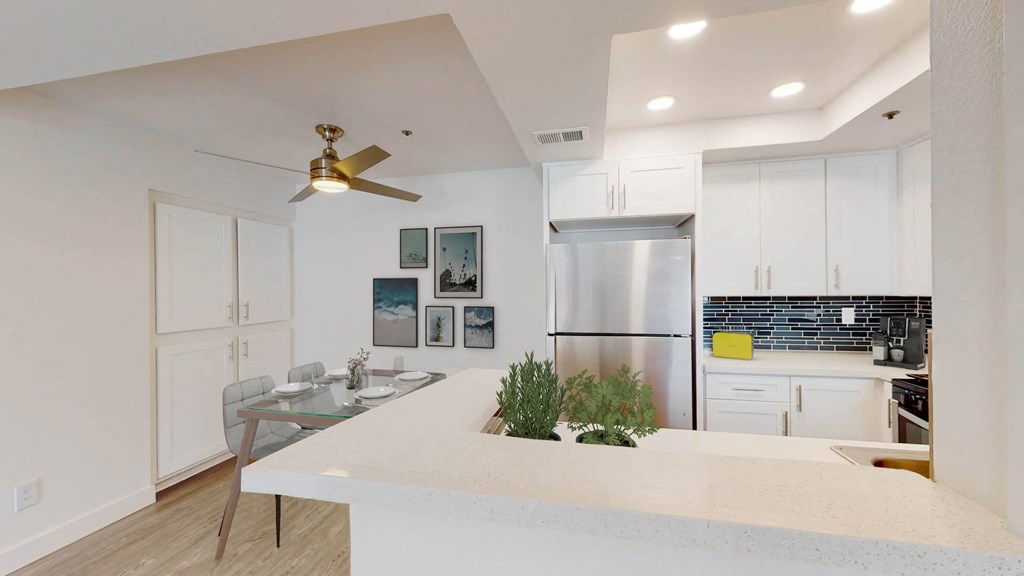 a kitchen with a white counter top and a stainless steel refrigerator