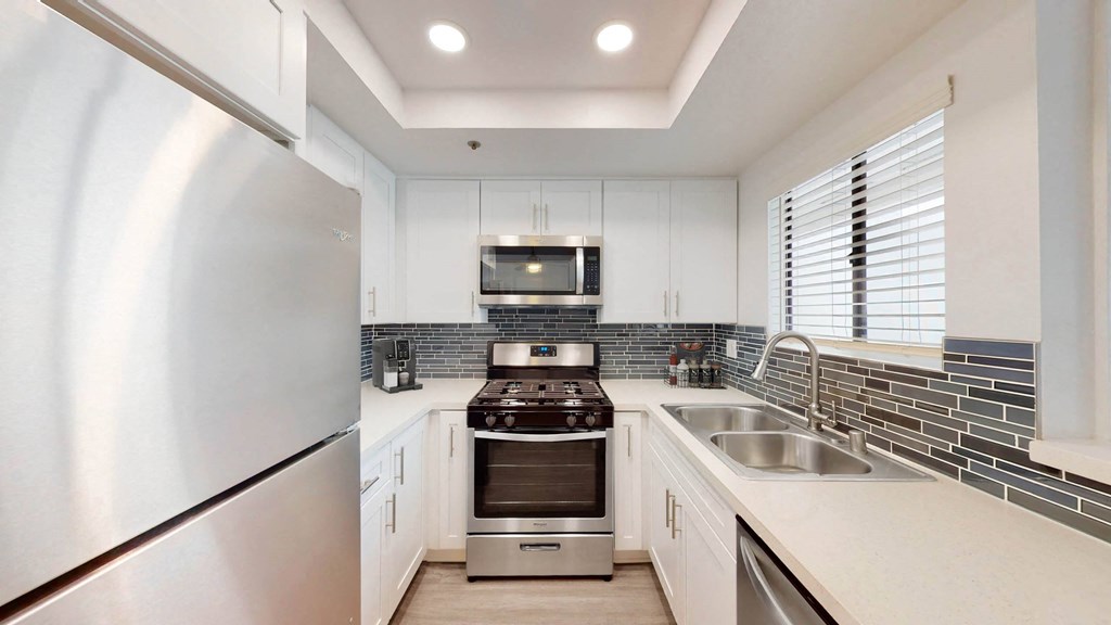 the kitchen has stainless steel appliances and white cabinets