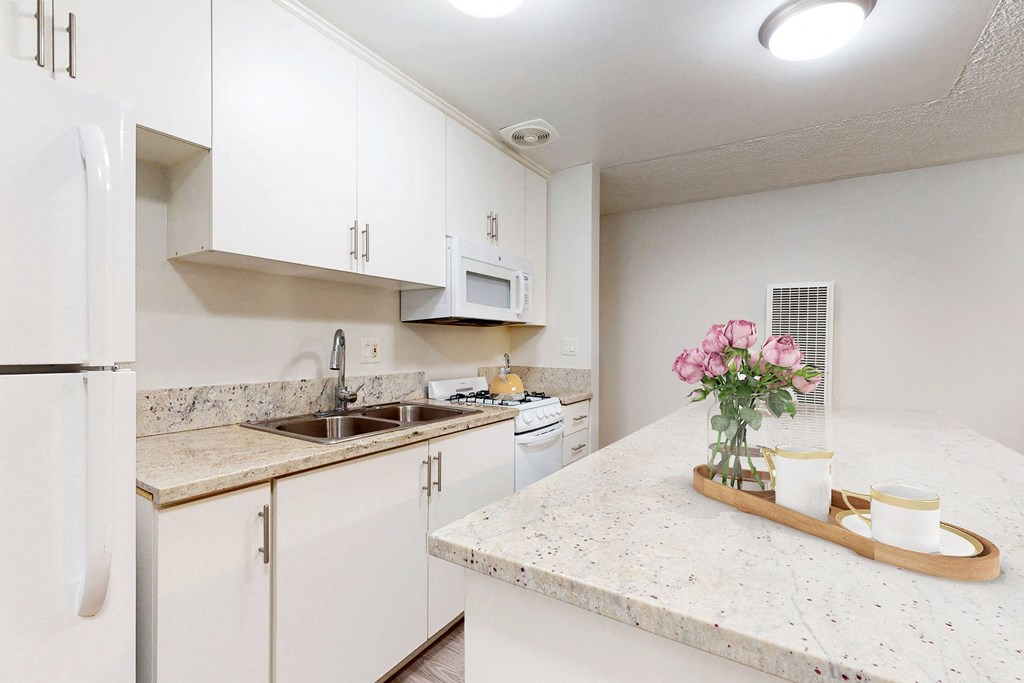 a kitchen with white cabinets and granite counter tops at Casa Granada, Los Angeles, CA