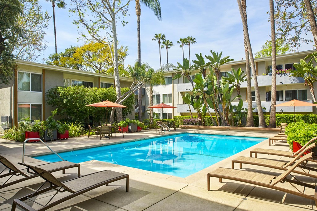 a swimming pool in front of a hotel with palm trees