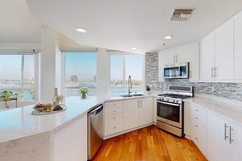 A modern kitchen with white cabinets and a marble countertop.