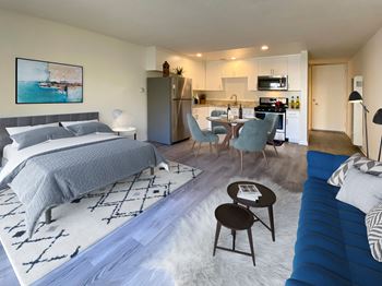 a bedroom and living room with a bed and a kitchen