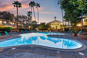 A round swimming pool surrounded by chairs and trees at Mediterranean Village Costa Mesa, Costa Mesa, CA