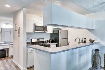 A kitchen with white cabinets and a marble countertop at Mediterranean Village Costa Mesa, Costa Mesa, CA