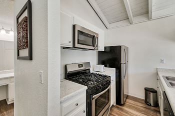 A kitchen with a black stove top oven and a black refrigerator at Mediterranean Village Costa Mesa, Costa Mesa, CA