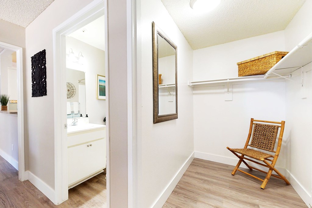 A white bathroom with a wooden chair and a mirror at Mountain Vista, Victorville, CA