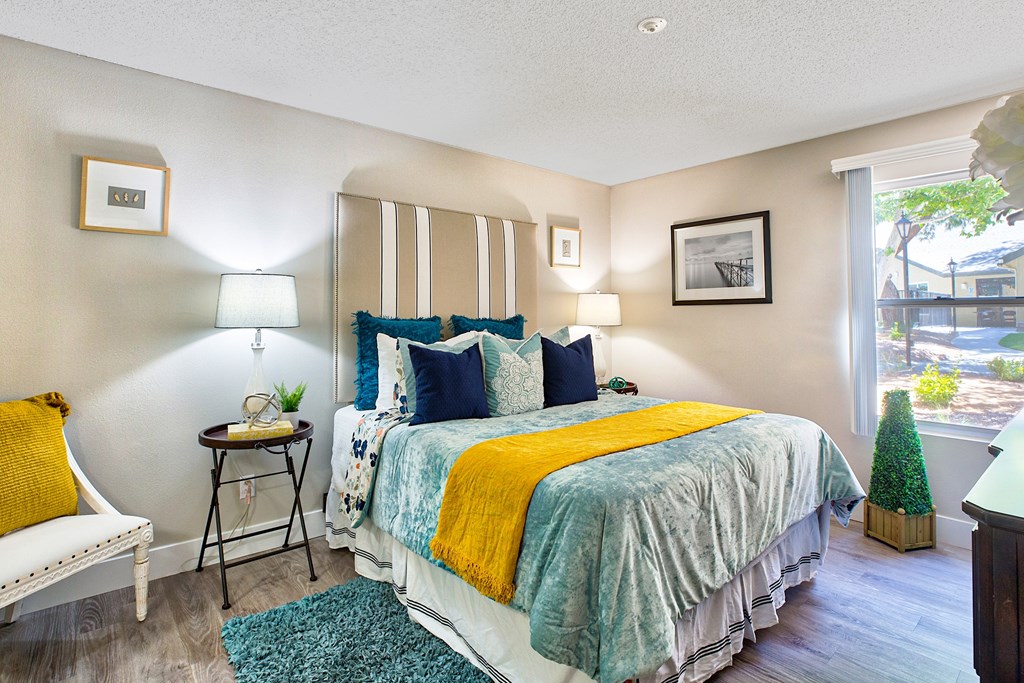 A bedroom with a bed, nightstand, and a chair at Mountain Vista, Victorville, CA
