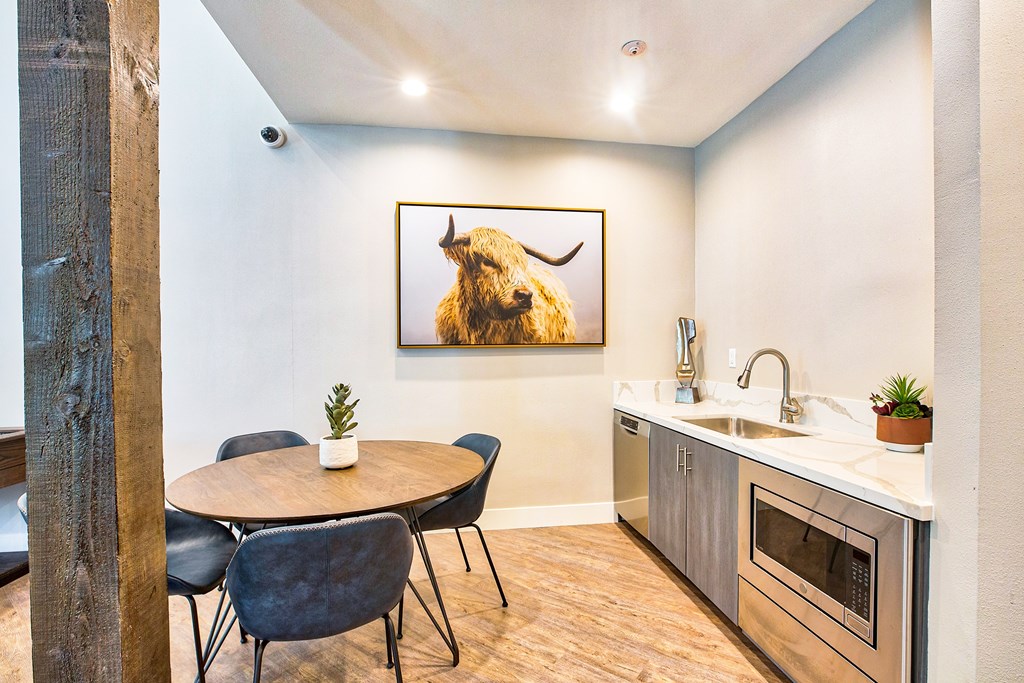 A kitchen with a table and chairs and a painting of a bison on the wall.