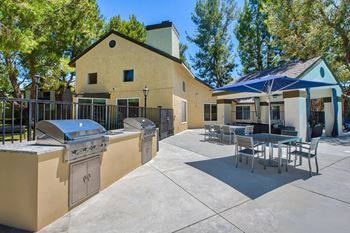 A patio with a table and chairs is surrounded by a fence and a house.