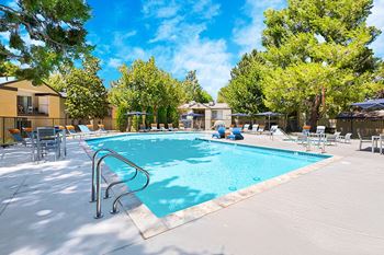 A large outdoor swimming pool surrounded by trees and lounge chairs.
