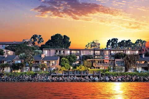 A row of houses are built on a rocky shore.