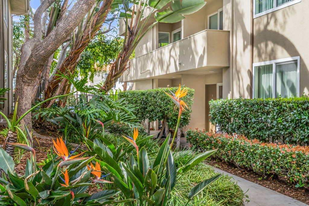 A building with a balcony is surrounded by green plants and trees at West Park Village, Los Angeles, CA