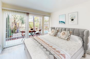 A bedroom with a large bed and a table outside at West Park Village, Los Angeles, 90025