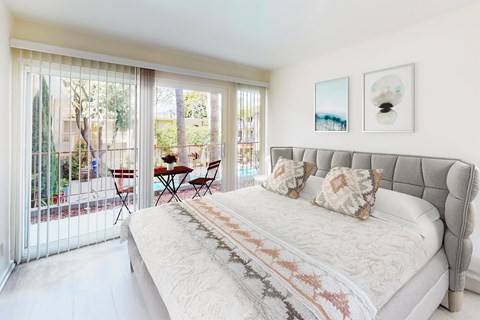 A bedroom with a large bed and a table outside.