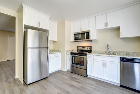 A kitchen with a refrigerator, oven, and microwave.