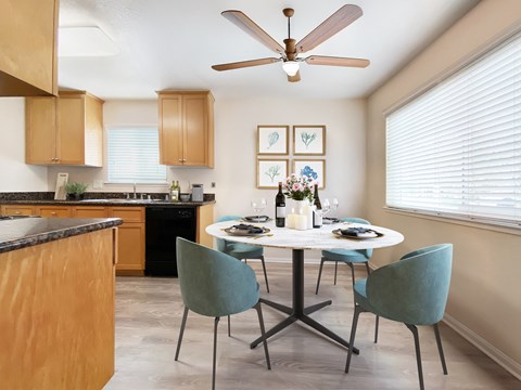 A kitchen with a table set for two and a ceiling fan.