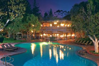 A large swimming pool in front of a lit building at night.