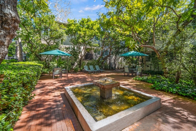 a courtyard with a fountain and a patio with umbrellas