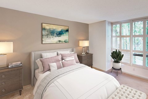A bedroom with a large bed, a nightstand with a lamp, and a painting on the wall.