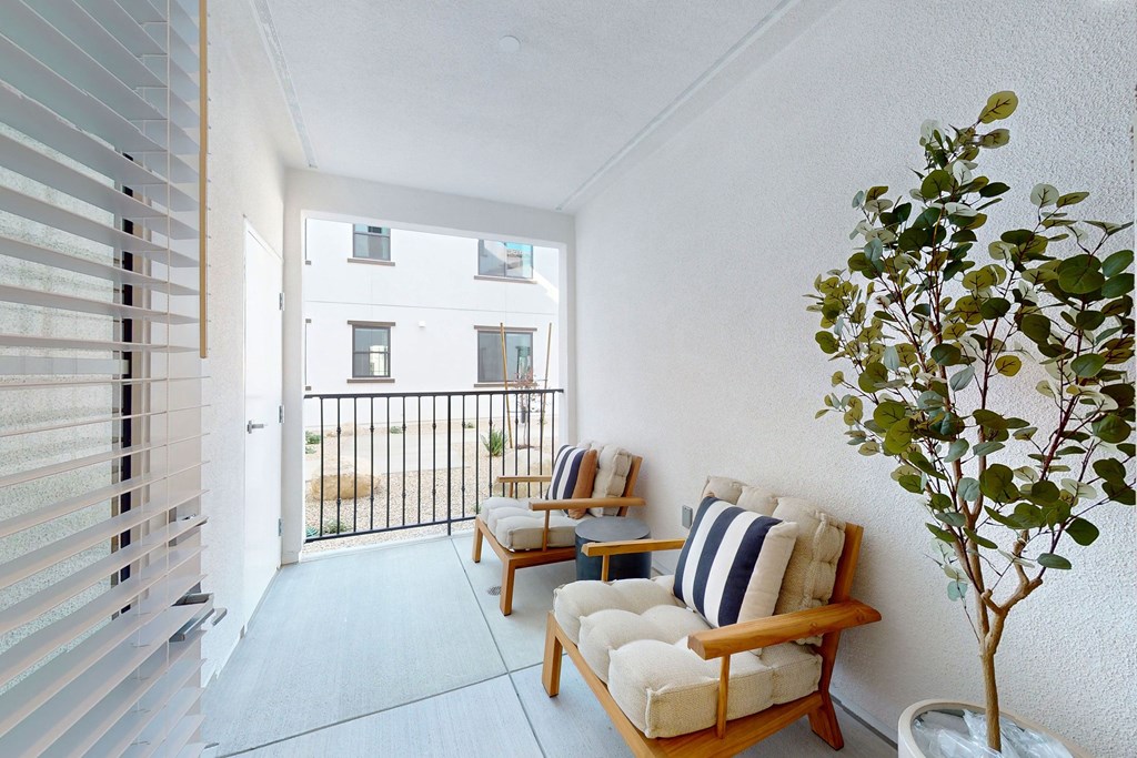 A balcony with two chairs and a table with a tree in a pot at The Villas at Anacapa Canyon, Camarillo, 93012
