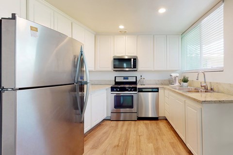 A modern kitchen with a stainless steel refrigerator and white cabinets.