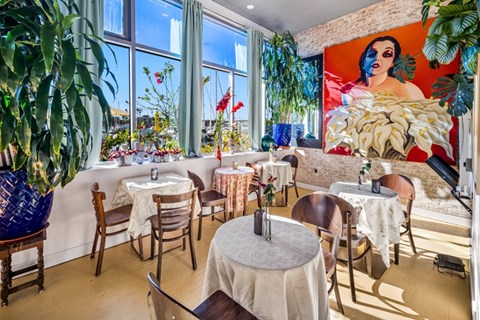 A restaurant with tables and chairs and a large mural on the wall.
