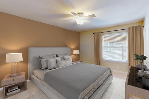 A bedroom with a large bed, a ceiling fan, and a nightstand with a lamp.